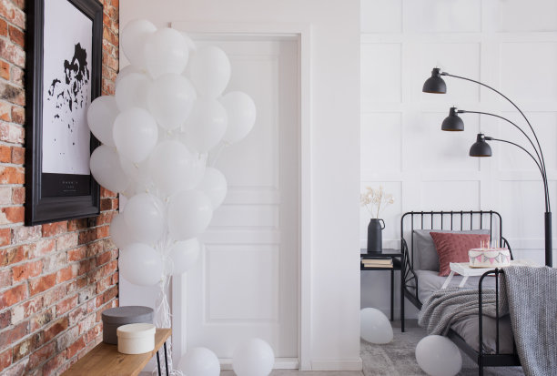 红砖墙上的海报和卧室内部的气球，床上有黑色的灯。真实的照片图片下载