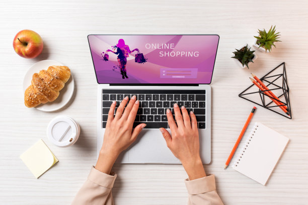 这张照片拍摄的是一位女商人正在用笔记本电脑上网购物，桌上放着咖啡、苹果和羊角面包图片下载