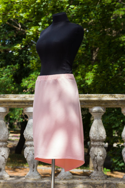 模特穿着粉红色裙子。天然面料的夏季裙。妇女的服装以绿树为背景图片下载