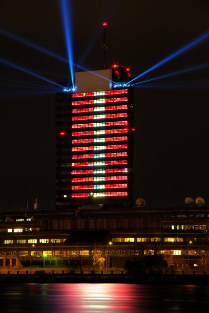 拉脱维亚电视大楼明亮的红白灯光。蓝点光束从屋顶上投射出来。图片下载