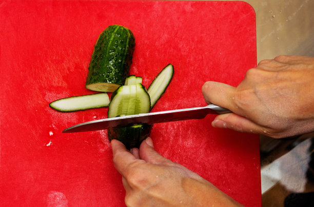 一位妇女正在切黄瓜做沙拉。图片下载