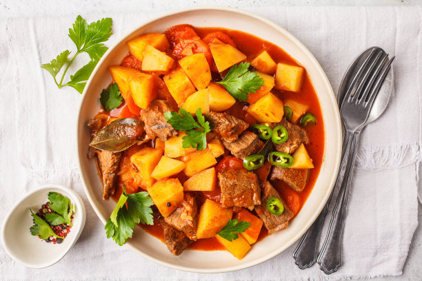 香辣牛肉和番茄土豆炖在白色盘子里，俯视图。图片下载