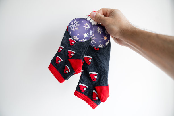 一双温暖的新年假期风格的袜子在一个人的手中，在一个灯光背景的墙壁上。图片下载