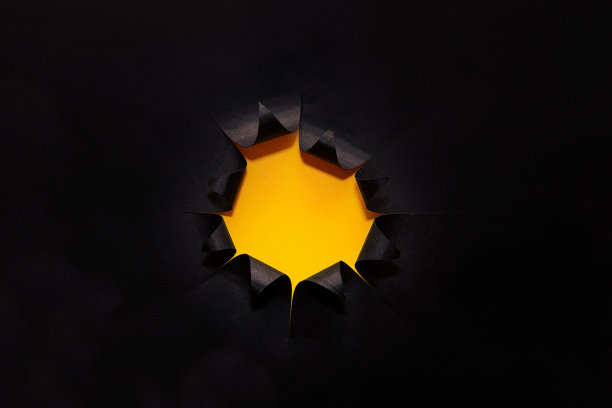 突破纸孔黄色背景，孤立在黑色。图片下载