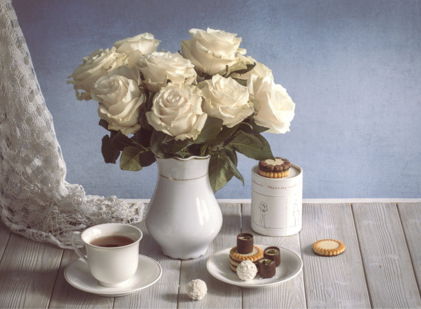 白色花瓶里插着玫瑰的静物画板，蓝色墙壁图片下载