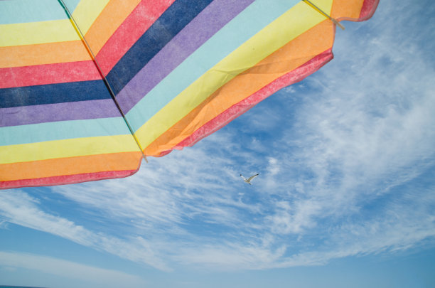 一张彩虹彩色伞与蓝色的夏季天空和白云与海鸥的照片图片下载