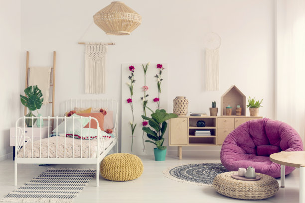 时尚的粉红色长沙发在优雅的波西米亚卧室的中间，墙上有流苏，花板和带枕头的单金属床，真实的照片图片下载