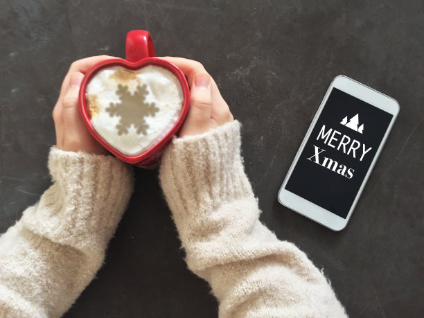 女孩拿着咖啡杯，洒着雪花和手机图片下载