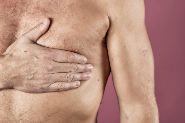 患有胸痛、心脏病发作或疼痛痉挛的男子，在粉红色的背景上以疼痛的表情按压胸部。严重的心痛图片下载