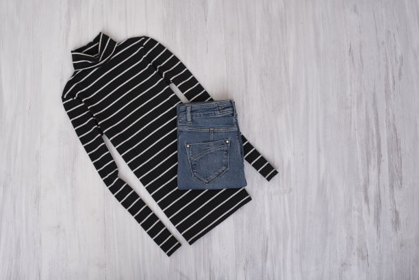 黑色条纹高领毛衣和牛仔裤上的木制背景。时尚的概念图片下载