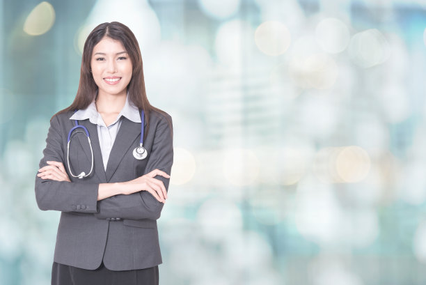 美丽微笑的女医生握着听诊器双手交叉。医疗帮助或保险概念。医生在等病人检查。图片下载