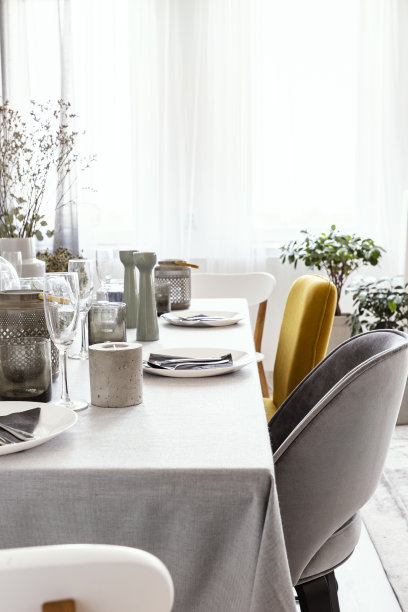餐桌与餐具的真实照片，蜡烛和灰色和黄色的椅子站在明亮的餐厅内部与窗户与窗帘图片下载