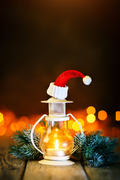 圣诞快乐，恭贺新禧。蜡烛和圣诞玩具放在木桌子上，背景是一个花环。散景。有选择性的重点。背景与复制空间。图片下载