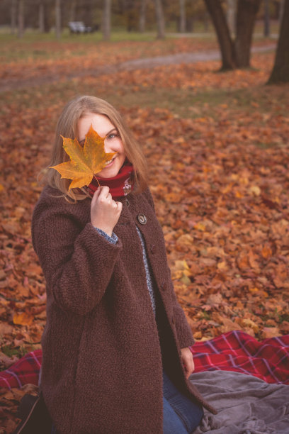 秋日公园：女子手持落叶图片下载