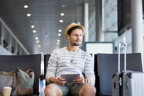 年轻帅气的男子在机场休息室里使用平板电脑图片下载