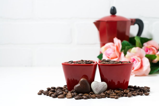 咖啡豆和巧克力糖果旁的红色杯子图片下载