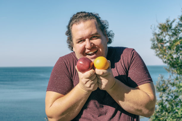 有趣的胖子在海洋上吃水果。度假、减肥和健康饮食图片下载