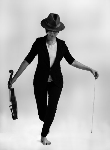 女士穿着黑色的套装和棕色的帽子，站在舞台上，手里拿着小提琴和弓，准备演奏，艺术音调图片下载