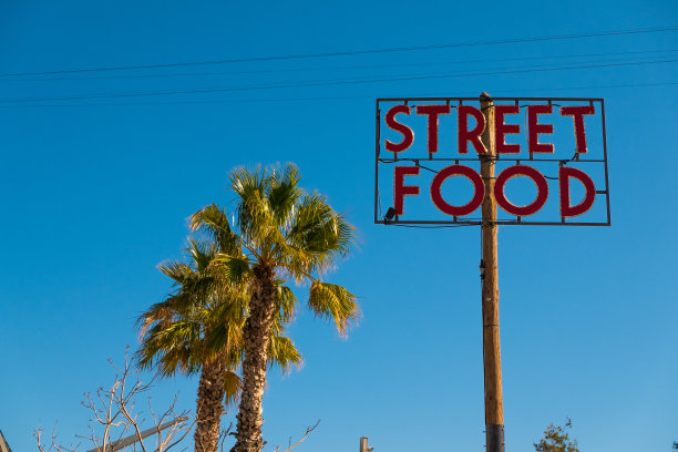 在阳光明媚蔚蓝的夏日，街头小吃的招牌上挂着棕榈树图片下载