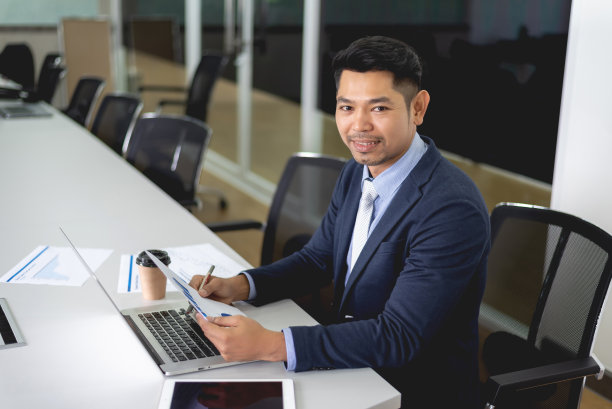 年轻的商人微笑着坐在会议室里图片下载