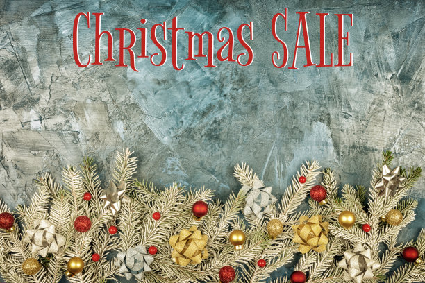 圣诞作文，雪花覆盖冷杉树枝。它们用金色的蝴蝶结、金色的圣诞球和红色的浆果来装饰。题词圣诞特卖在深蓝色的背景与纹理腻子。节日的传单。图片下载