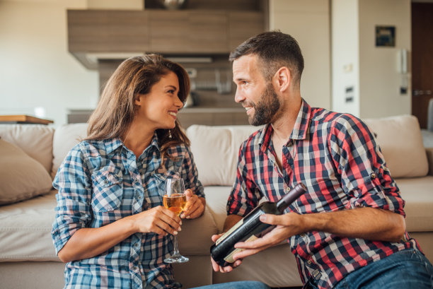 一对帅气的情侣互相看着对方，手里拿着酒瓶和酒杯图片下载