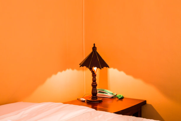 这盏木灯被放在一张旧的棕色木桌上，旁边是一个绿色的电话。的床上图片下载