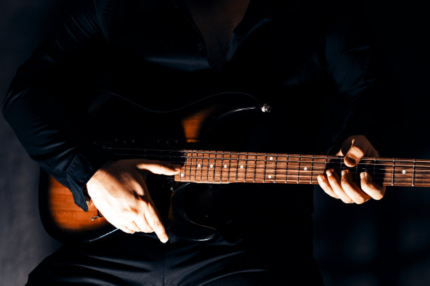 音乐家手中的六弦电吉他。音乐家的手指拨动琴弦。图片下载