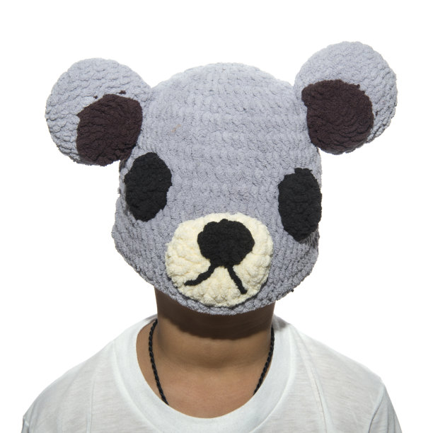 那男孩把一顶编织的帽子戴在脸上。图片下载