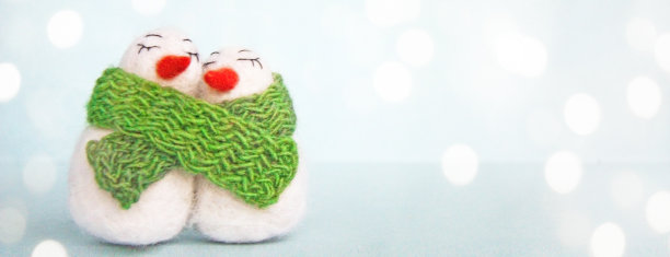 白色的幸福的爱的毛线雪人与绿色针织围巾在明亮的蓝色背景图片下载