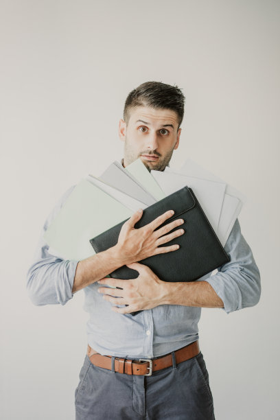 一个迷茫的年轻商人拿着一堆文件的肖像图片下载