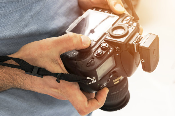 数码单反相机男性手中。摄影师拍摄手近。男摄影师制作照片。男性的双手握着相机的特写镜头图片下载