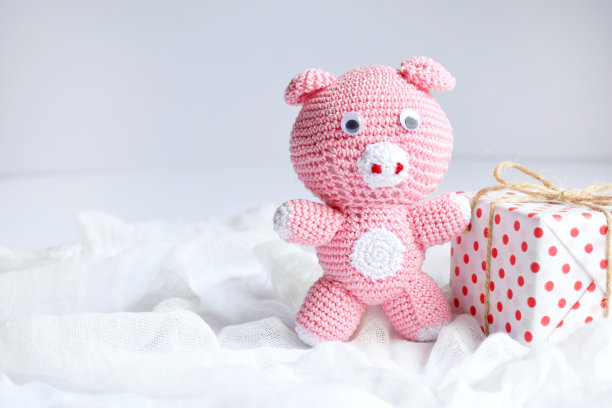 粉色小猪，象征2019，白色背景上的礼物。恭贺新禧，寄圣诞卡。儿童钩针玩具。在假期亲手制作手工艺品。DIY的概念。本空间图片下载