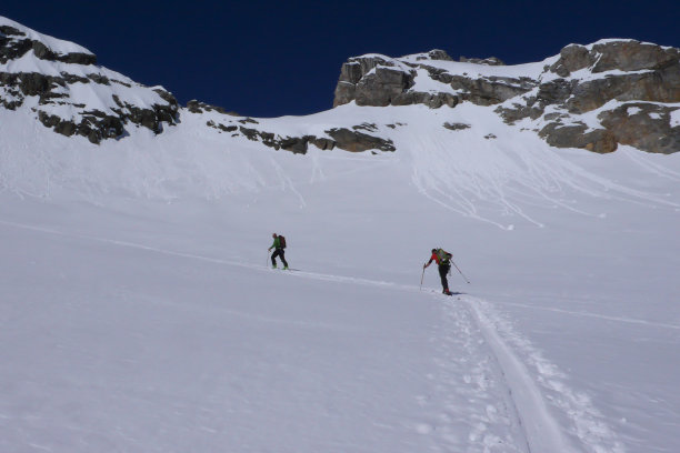 高山导游在野外滑雪旅游，带领客户到一个高高山的顶峰图片下载