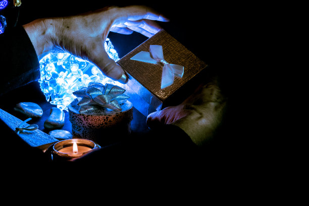 女人手握礼物的特写，反对照明的圣诞节装饰图片下载