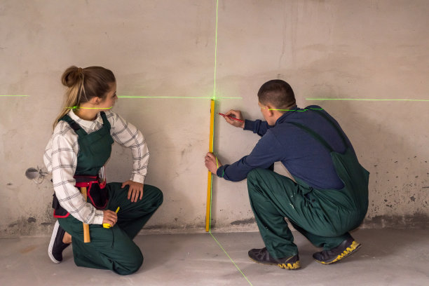 工人用激光水平仪测量墙壁图片下载