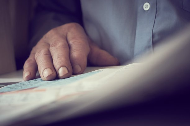 白发苍苍的老人正在家里看报纸。彩色照片。图片下载