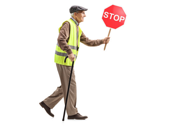老人拄着拐杖，穿着安全背心，举着停车标志图片下载