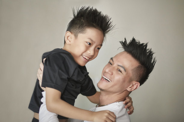 微笑的父亲背着儿子靠墙图片下载