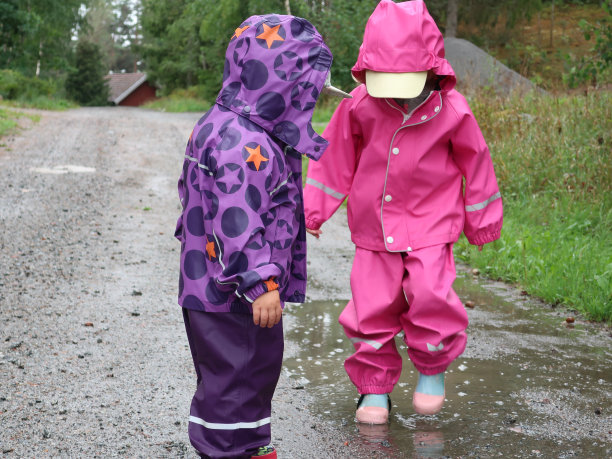 孩子们在泥泞的水坑里玩耍跳跃。图片下载