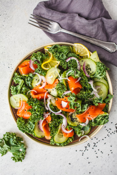 盐鲑鱼(鳟鱼)和羽衣甘蓝沙拉在一个白色的盘子在一个白色的背景，俯视图。图片下载