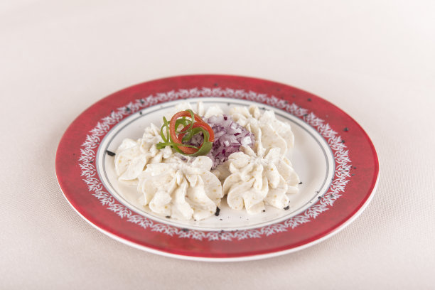 鱼子沙拉，用红洋葱，点缀绿叶和红叶，放在白红相间的盘子上，背景光图片下载