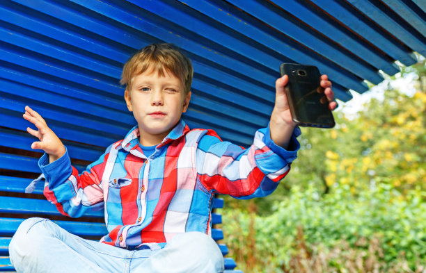 快乐的男孩玩得很开心，拍下他们自己，在夏天的操场上玩手机图片下载