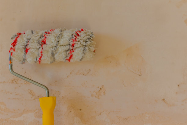 在浅米色混凝土背景上使用滚筒刷漆图片下载