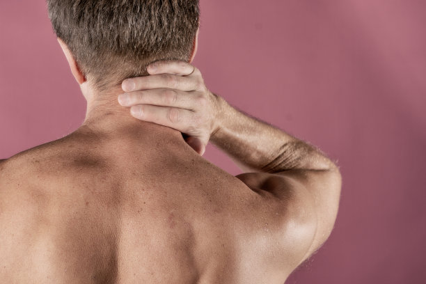 一名男子痛苦地扼住脖子，孤立在粉红色的背景下。降低颈部疼痛。赤裸上身的男人摸着脖子痛图片下载