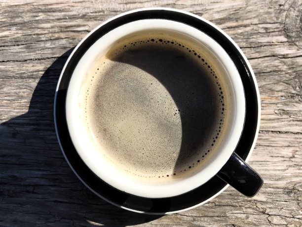 阳光下的黑咖啡放在木桌上图片下载