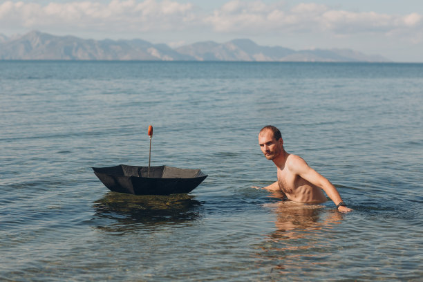 一个年轻人撑着伞在海里游泳图片下载