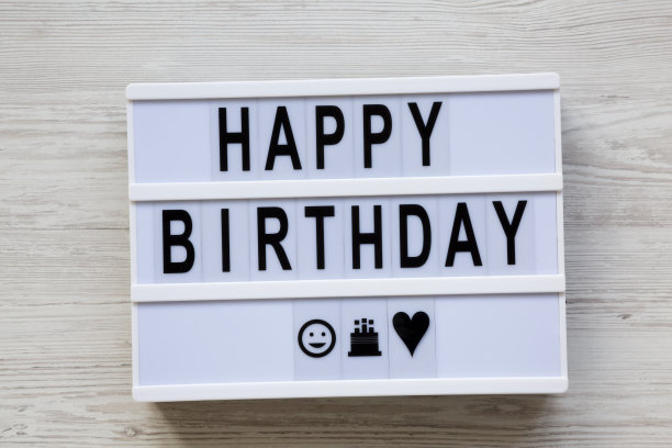 灯箱与文字“生日快乐”在白色木制表面，俯视图。平躺着，从上面俯视。图片下载
