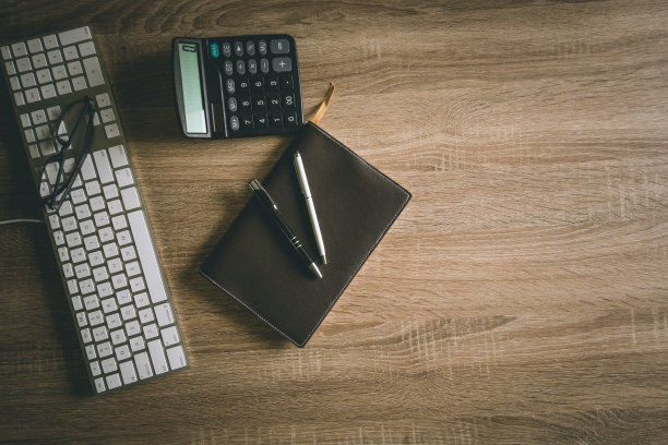 办公桌边，商务用键盘，笔记本，笔，眼镜，计算器。俯视图背景的复制空间。图片下载