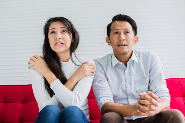 亚洲的丈夫和白种人的妻子一起看电视节目和恐怖的家庭活动的概念图片下载